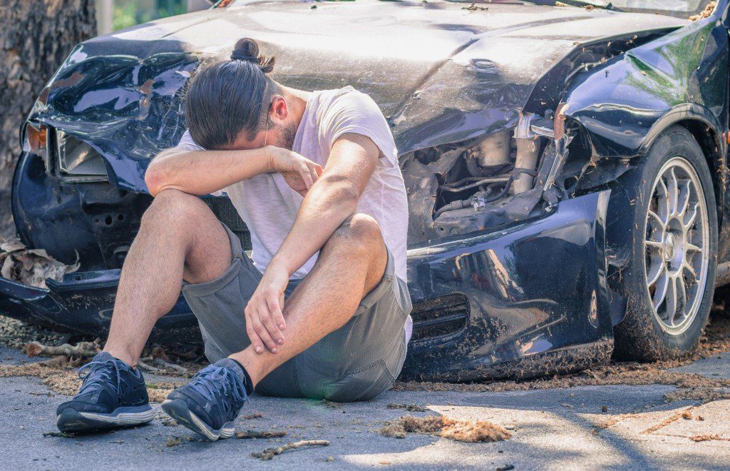man in front of a wrecked car