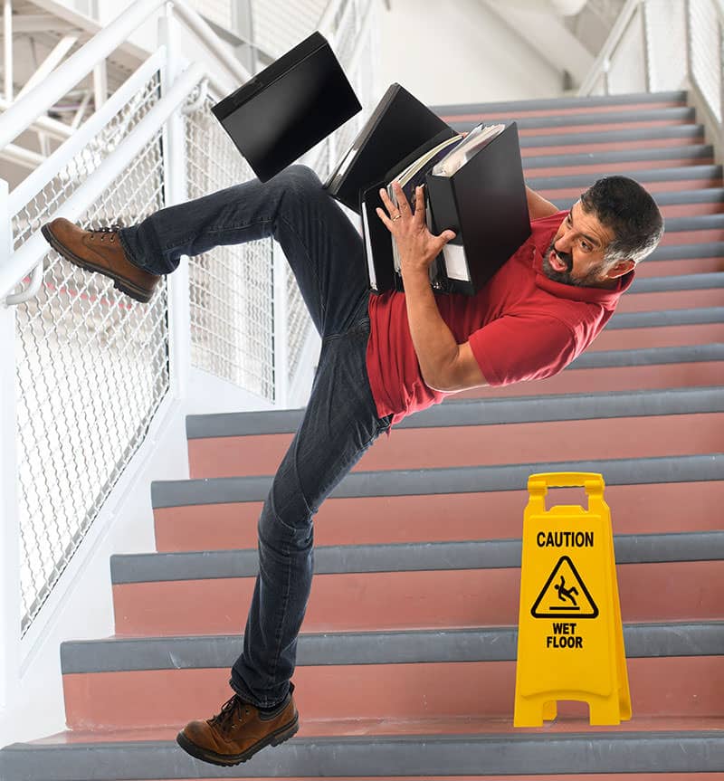 A man falling down stairs with two laptops.