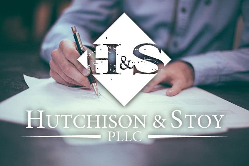 A person writing on paper with the words hutchison & stone pllc in front of them.