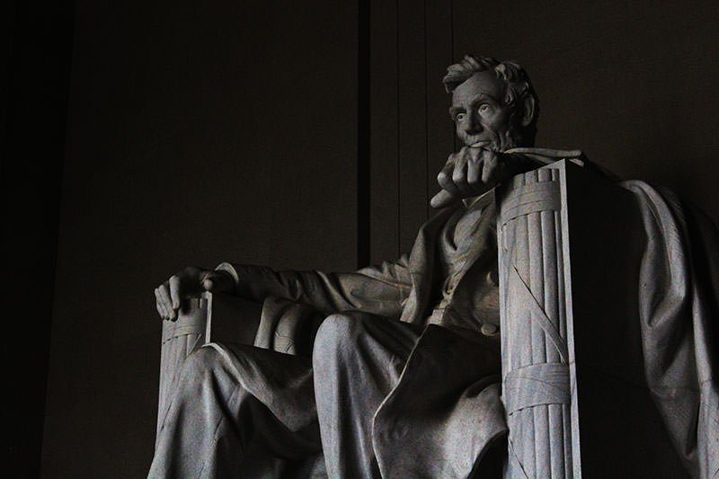 A statue of abraham lincoln sitting in the dark.