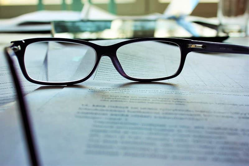 A pair of glasses sitting on top of some papers.