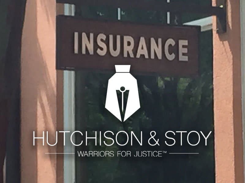A sign that says insurance and hutchison & stoy warriors for justice.
